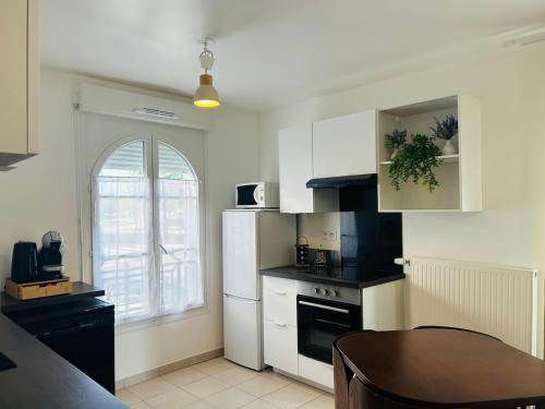 a kitchen with a white refrigerator and a table at Warm and welcoming apartment in Serris