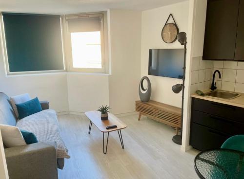 un salon avec un canapé et une télévision dans l'établissement Azur Éden Studio avec Piscine à Deux Pas de la Plage, à Cannes