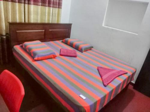a bed with two pillows on it with a red chair at Kelaniya Guest House in Peliyagoda