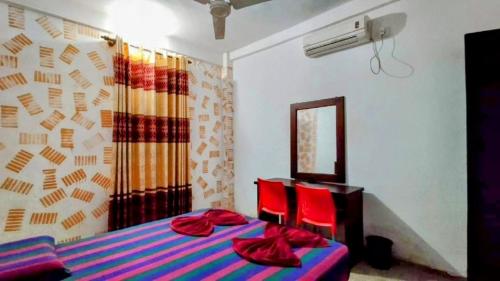 a bedroom with a bed and two red chairs at Kelaniya Guest House in Peliyagoda