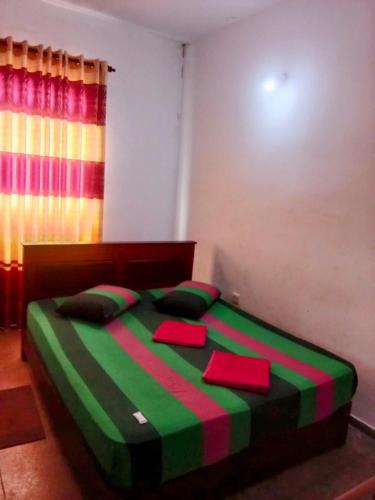 a bedroom with a bed with green and pink stripes at Kelaniya Guest House in Peliyagoda