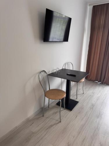 a table with two chairs and a television on a wall at Spa Hotel Alpin in Solotvyno