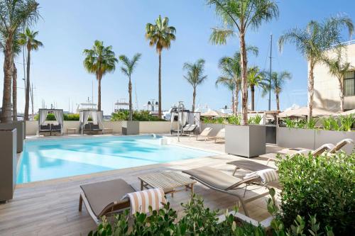 a swimming pool with chaise lounge chairs and palm trees at Riviera Marriott Hotel La Porte De Monaco in Cap d'Ail