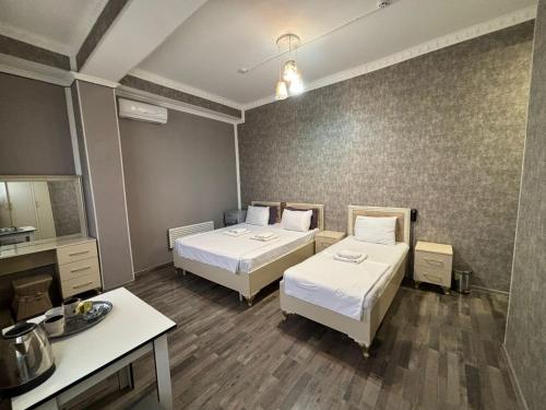a room with two beds and a table in it at Delfin Hotel & Restaurants & Spa in Ganja