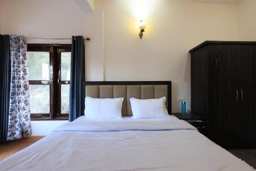 a bedroom with a large bed with a window at Nature Roar Forest Resort ,Nainital in Nainital