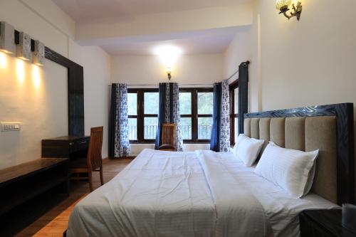 a bedroom with a bed and a desk and windows at Nature Roar Forest Resort ,Nainital in Nainital