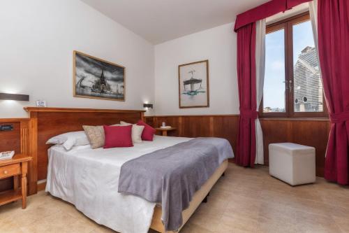 a bedroom with a large bed with red curtains at Hotel Duomo in Orvieto