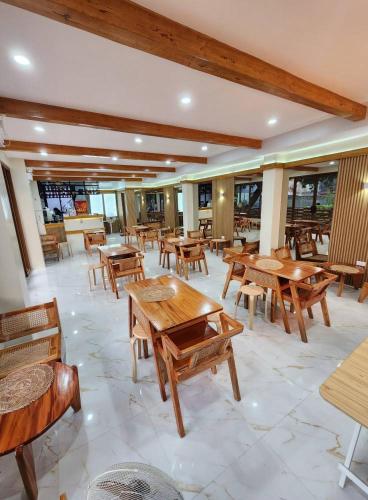 a restaurant with wooden tables and chairs and windows at The Tree House - Connecting Loft Units Govantes in Vigan
