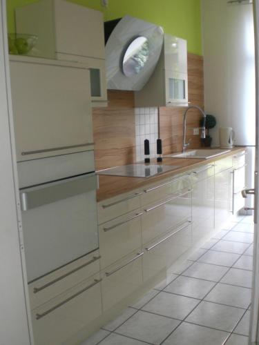 a kitchen with white cabinets and a sink at Das Stadthaus, mit Terrasse und Garten in Diepholz