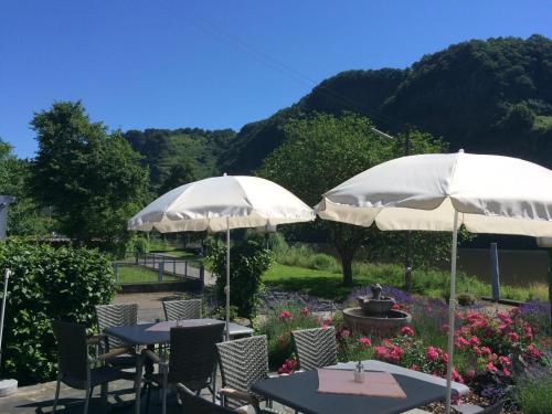 two tables and chairs with umbrellas in a garden at Alt Reinsport in Piesport
