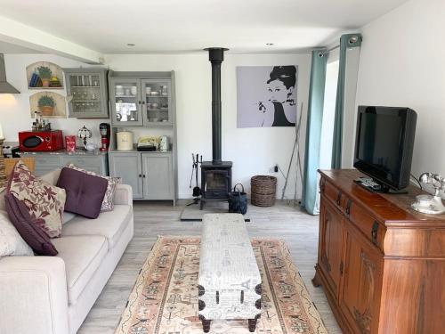 a living room with a couch and a tv at Charming Dog-Friendly Guesthouse in Sidbury