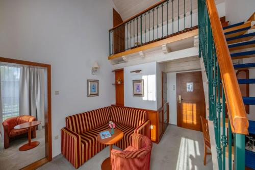 a living room with a couch and a staircase at Bakony Resort - a Felnőttbarát Hotel - Szarvaskút Vendégpark in Zirc