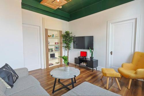 a living room with a couch and a table and a tv at Royale 1918, 6bdr, game room, net, pool & more in Beaupré