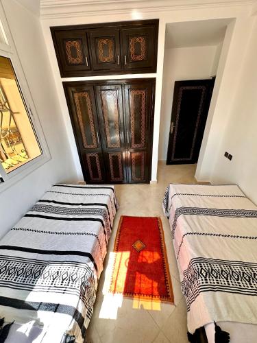 two beds in a room with a door at Balance Surf Morocco , Quality rooms , Moroccan food , Activities in Aourir