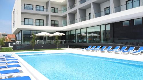 un hotel con piscina, sillas y un edificio en Hotel Monte Lírio, en Espinho