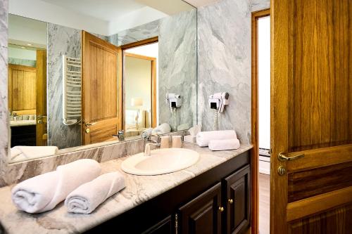 une salle de bain avec un lavabo et un grand miroir dans l'établissement Hôtel Les Jardins, à Lucciana