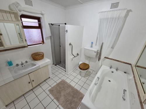 a bathroom with a tub and a sink and a shower at Volgens Plan Family Holiday Home in Little Brak River in Reebok