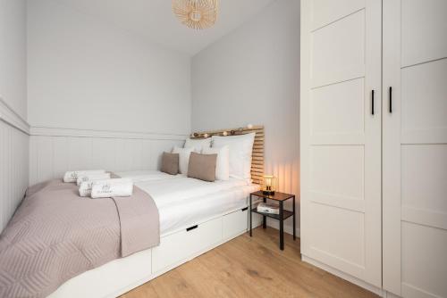Dormitorio blanco con cama grande y mesita de noche en Flatbook Apartamenty - Sztutowo Perła Mierzei II, en Sztutowo