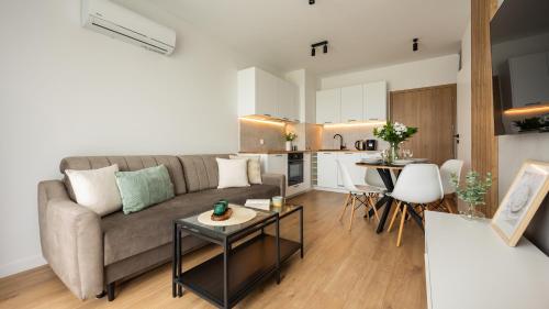 una sala de estar con un sofá y una mesa en Flatbook Apartamenty - Sztutowo Perła Mierzei II, en Sztutowo