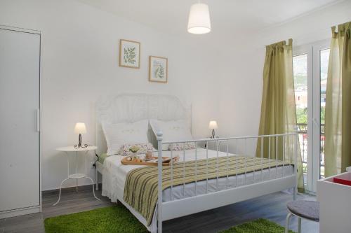a white bedroom with a white bed and a balcony at Apartment Luka in Makarska