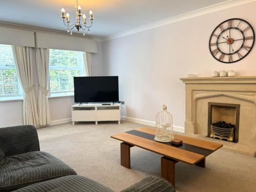 a living room with a fireplace and a clock on the wall at Cherry Tree Family Home in Telford
