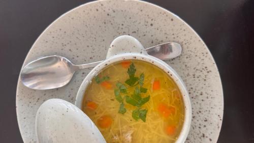 a bowl of soup sitting on a plate with spoons at Spa Hotel Alpin in Solotvyno