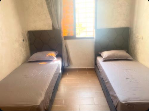 two beds in a small room with a window at Appartement-suite- de standing 10 min de la plage in Agadir