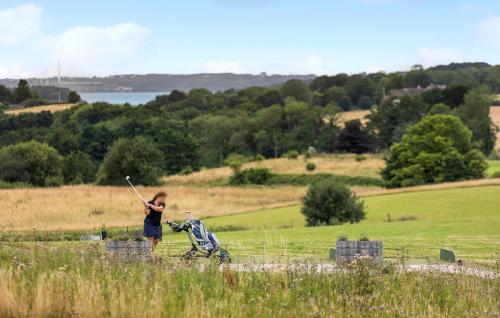 a woman standing in a field holding a golf club at Gorgeous Home In Gråsten With Sauna in Gråsten