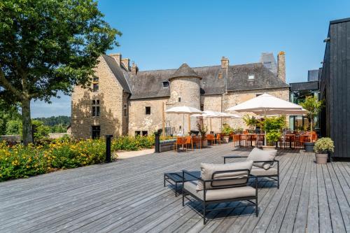een terras met stoelen en parasols voor een kasteel bij La Maison OBONO Hôtel & Spa in Le Bono