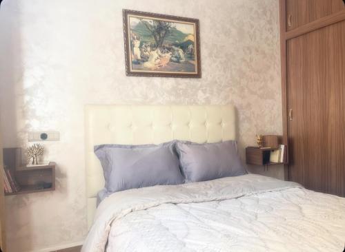 a bedroom with a bed with a painting above it at Appartement-suite- de standing 10 min de la plage in Agadir