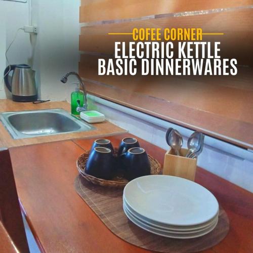a kitchen counter with plates and utensils and a sink at The River House - Govantes Guesthouse in Vigan