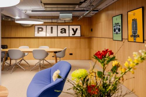 a room with a table and chairs and a play sign at The Social Hub Rotterdam in Rotterdam