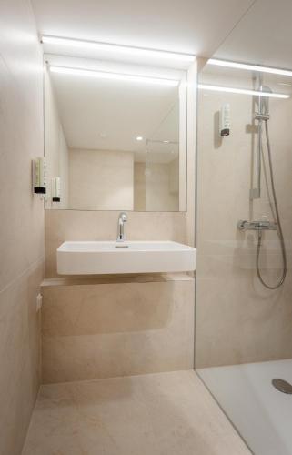 a bathroom with a sink and a shower at Grand Pods - Capsule Hotel in Vienna