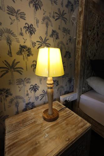 a lamp on a wooden table in a bedroom at Vanaswara in Kolād