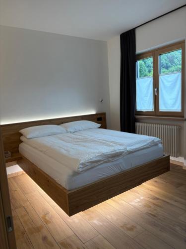 a bedroom with a large bed with a large window at Alp House Dolomiti in Croviana