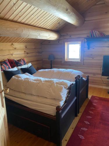 a bedroom with a bed in a log cabin at Stor velutstyrt laftehytte med usjenert uteplass, flott utsikt og Jacuzzi in Eggedal