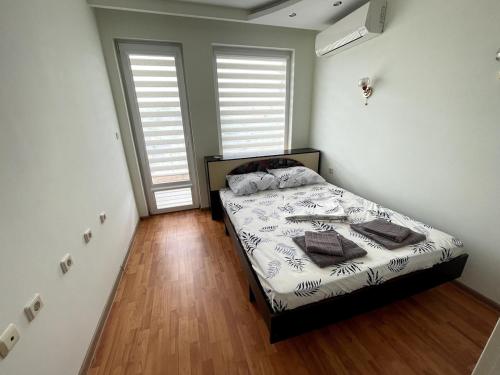 a bedroom with a bed and two large windows at 2BR Garden Bay Apartment in Varna City