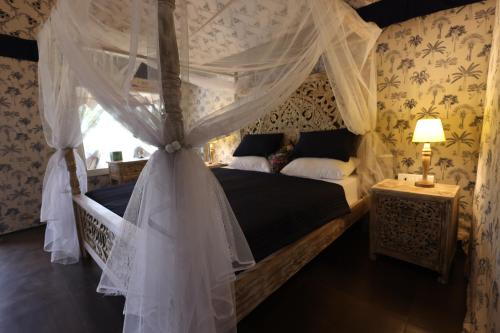 a bedroom with a canopy bed with white curtains at Vanaswara in Kolād