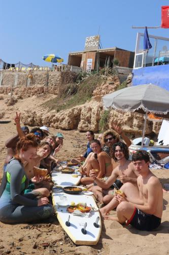 a group of people sitting on the beach eating food at Balance Surf Morocco , Quality rooms , Moroccan food , Activities in Aourir