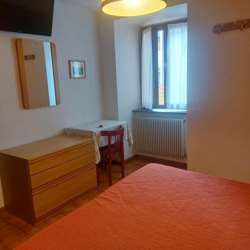 a bedroom with a table and a bed and a window at Hotel Paganella in Molveno