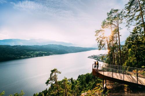 a bridge over a lake with two people standing on it at 3Traumhaftes Ferienhaus in bester Lage in Döbriach
