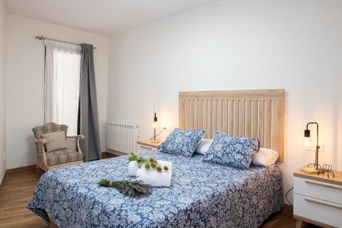 a bedroom with a bed with blue sheets and a chair at Apartamento rural Ca La Rumbeta en La Fresneda in La Fresneda