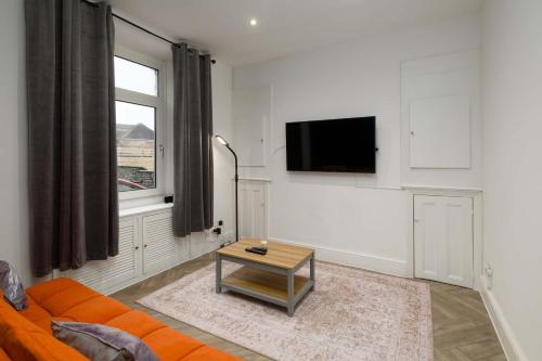 a living room with an orange couch and a table at Spacious 3 Bedroom Home in Central Skewen in Skewen
