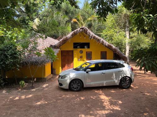 a small car parked in front of a yellow house at Vaakai Home Stay in Adampan