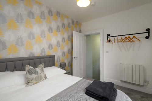 a bedroom with a bed with white sheets and a wall at Spacious 3 Bedroom Home in Central Skewen in Skewen