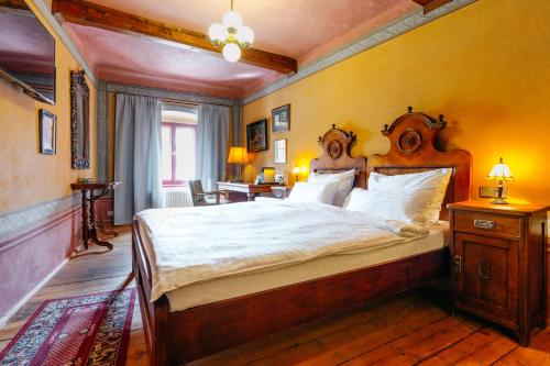 a bedroom with a large bed with a wooden headboard at Hotel Krčínův Dům in Český Krumlov