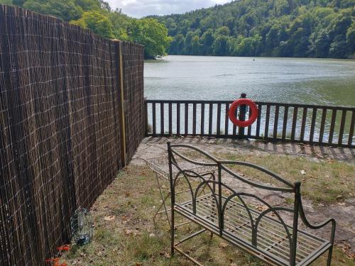 a fence with a bench next to a body of water at The Sharpham Boat House in Totnes