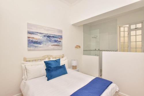 a white bedroom with a bed with blue pillows at Dalebrook Place Kalk Bay near Tidal Pool in Kalk Bay