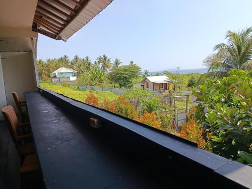 a balcony with a view of a garden at The Daun Puntik HomeStay in Pawenang