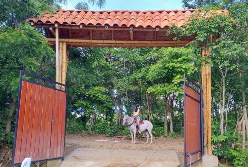 a woman riding a horse through a gate at El Eden Glamping cabañas Girardot in Girardot